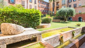 A courtyard with a water feature, stone benches, and lush greenery. - TREVI LUXURY PENTHOUSE with panoramic terrace (Roma)