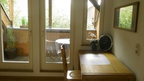 A small, well-lit room with a wooden table, a chair, and a window with a view of greenery. There is a clock on the wall and a small potted plant on the windowsill. - Apartment in the Schnakenstich, 80 m², 2 bedrooms, living room, eat-in kitchen... (Hochdorf)