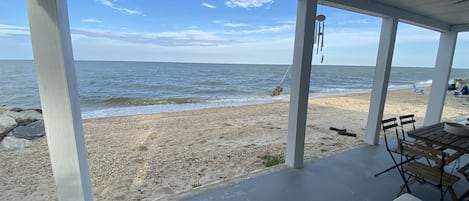 A covered outdoor area with a view of the beach and ocean.