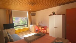 Een kamer met een bed, een bureau, een stoel, een televisie en een kledingkast.