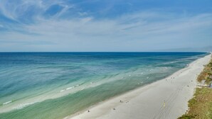En strand med klart vatten, en sandstrand och några få personer.