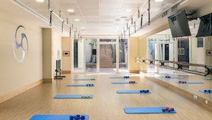 Un gimnasio con colchonetas azules, pesas y una amplia pared de espejos.