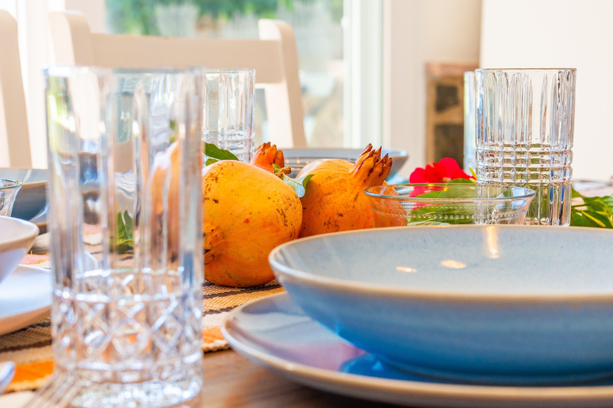 Une table à manger avec de la vaisselle en verre transparent, un bol bleu et une plante en pot.