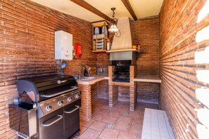 A compact kitchen with a gas stove, oven, and a brick oven.