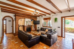 A living room with a fireplace, leather sofas, a television, and a view of the outside.