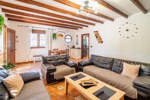 A living room with a sofa set, a coffee table, and a dining area with a table and chairs.