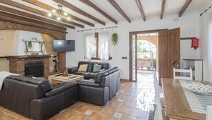 A living room with a fireplace, a sectional sofa, a TV, and a wooden ceiling.
