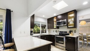 Une cuisine moderne avec des meubles de couleur sombre, des appareils électroménagers en acier inoxydable et un grand îlot central.