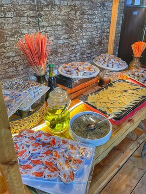 A buffet table with various food items, including trays of cheese, bowls of salad, and bottles of beverages. - Rum Oasis Luxury Camp (Wadi Rum)