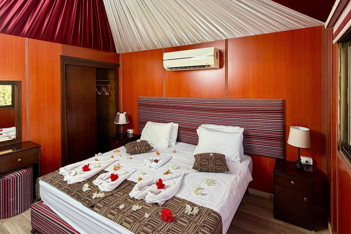 Ein Hotelzimmer mit einem großen Bett, Holzvertäfelung, einem Deckenventilator und einer Klimaanlage.