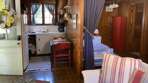 Ein gemütliches Zimmer im Blockhausstil mit Küchenzeile, Essbereich und Bett.