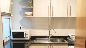 A compact kitchen with white cabinets, a microwave, a sink, and a dishwasher.
