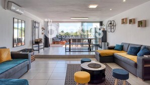 Un vaste espace de vie comprenant un canapé, une table basse et une table à manger. Une porte-fenêtre coulissante donne accès à un patio extérieur.