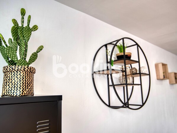 A cactus in a patterned pot on a black cabinet, a black metal shelf with a plant, and a white wall. - RENOVATED APARTMENT WITH A LARGE TERRACE FOR 4 PEOPLE (Platja d'Aro)