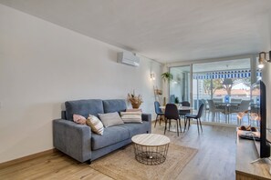 A modern living room with a grey sofa, a round coffee table, and a dining area with a table and chairs.