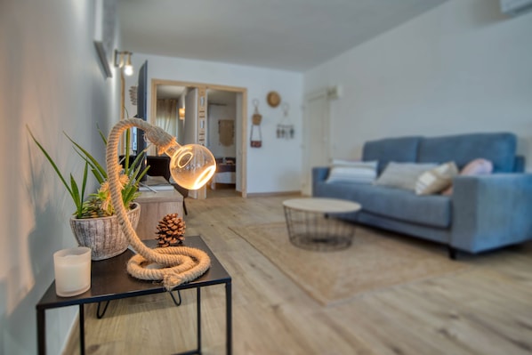 A modern living room with a blue sofa, a round coffee table, and a decorative lamp on a black side table.