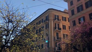 Un immeuble à plusieurs étages, doté de balcons, sous un ciel dégagé où le soleil brille de mille feux.