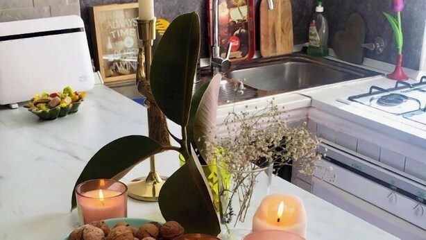 Un comptoir de cuisine orné de bougies, d’un bol de noix et d’une plante en pot.
