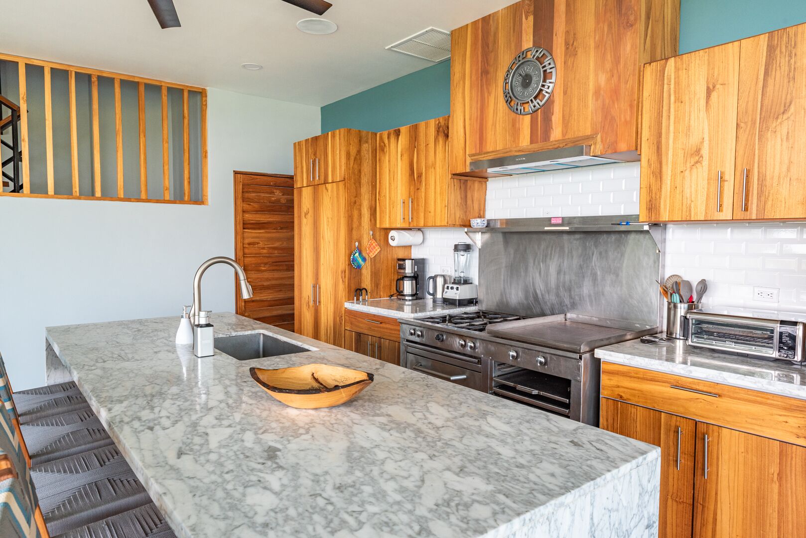 Una cocina moderna con armarios de madera, estufa de acero inoxidable y encimera de mármol.