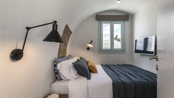 Ein Schlafzimmer mit Bett, Schreibtisch, Lampe, Fernseher und einem Fenster mit Aussicht.