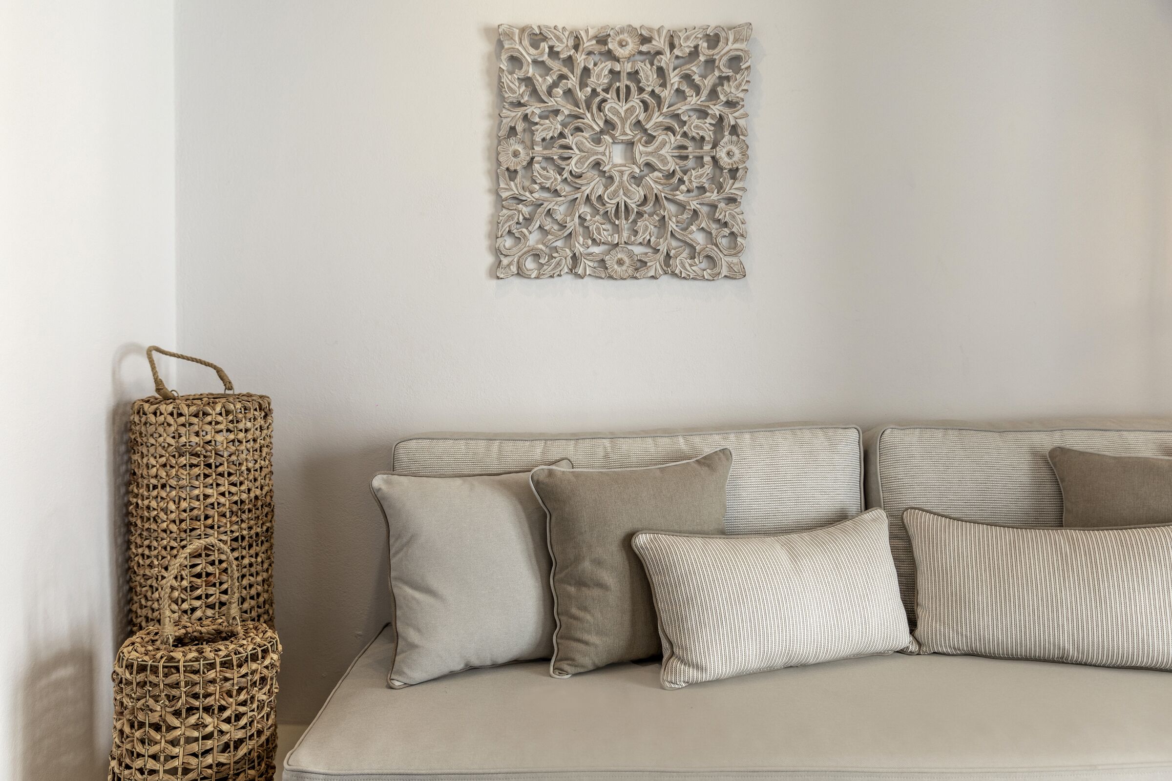 A neutral-toned living room with a beige sofa, striped and solid pillows, and a woven basket against the wall.