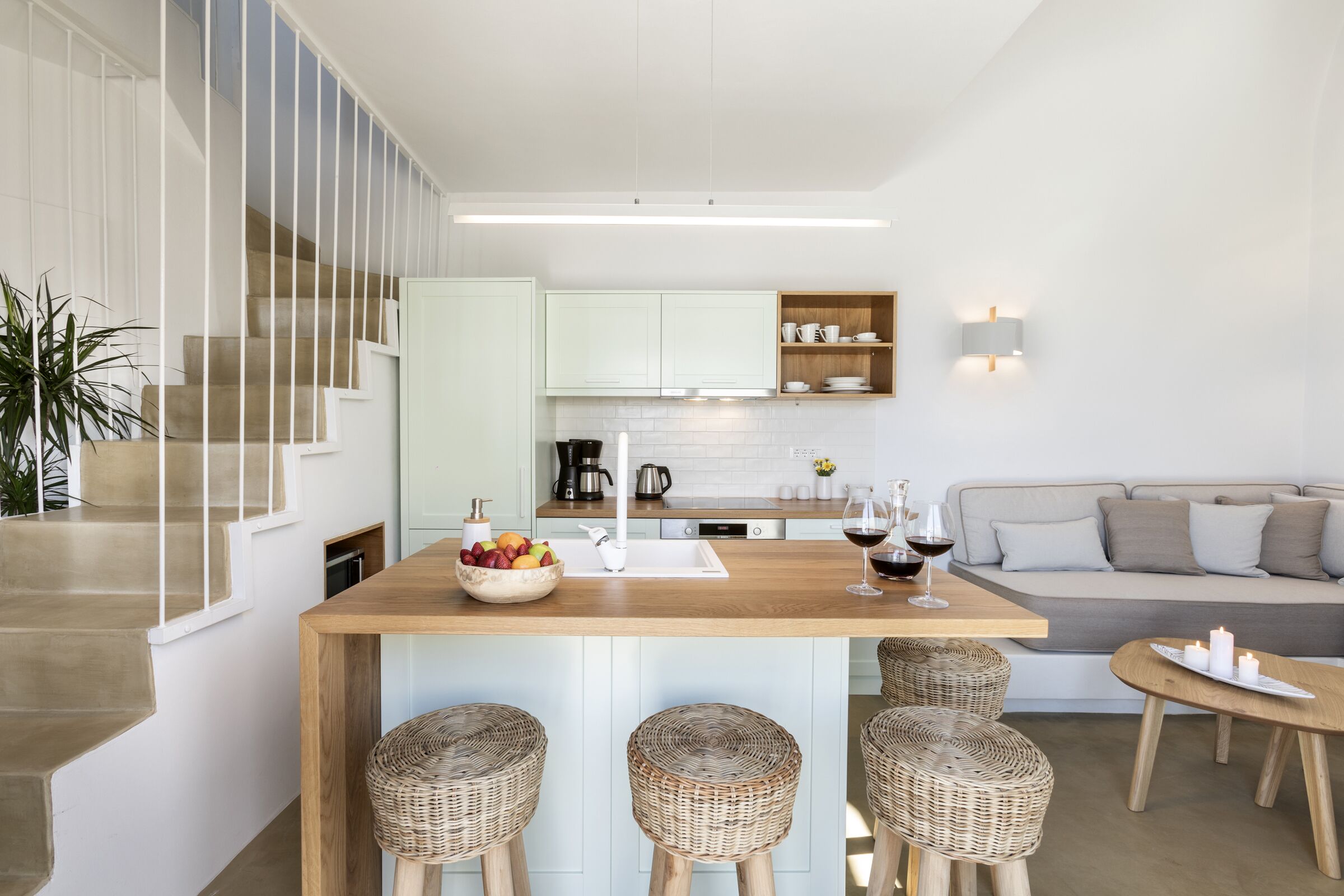 A modern kitchen with a central island, bar stools, and a dining area.