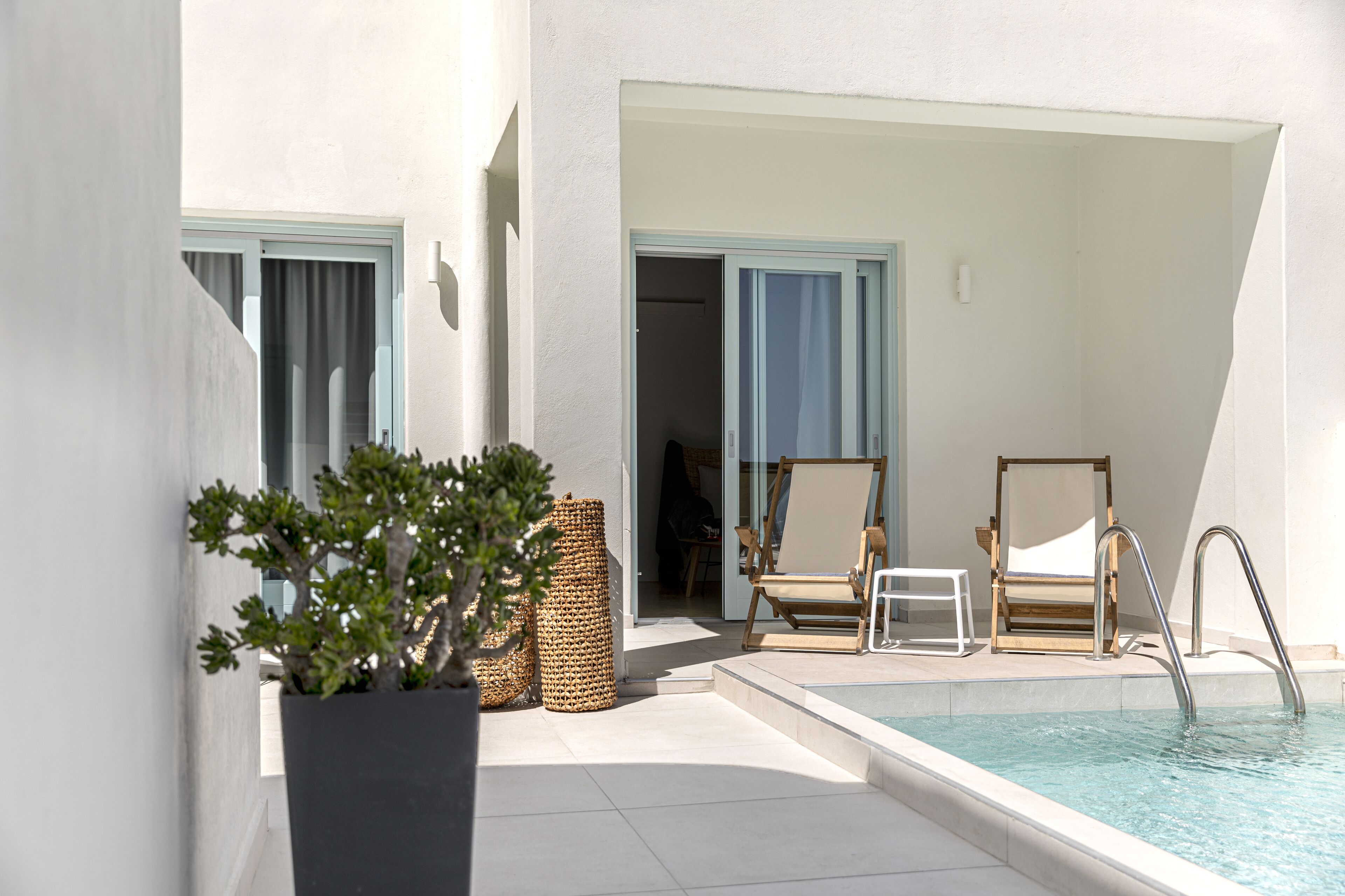 A poolside area with a lounge chair, a small table, and a potted plant.