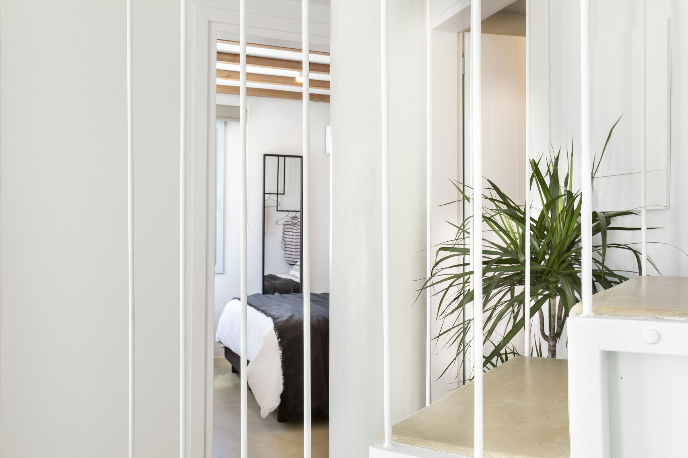 Une chambre à coucher moderne avec un lit, une plante sur la table de chevet et une armoire blanche.