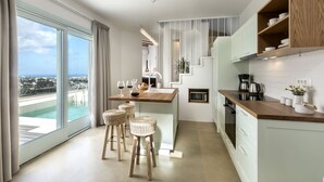 Une cuisine moderne dotée d’un grand îlot central, de tabourets de bar et offrant une vue sur l’océan.