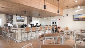 Un vaste espace dédié à la salle à manger, avec de hauts plafonds, un éclairage moderne et un bar situé au fond de la pièce.