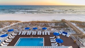 Un espace piscine doté de chaises longues et de parasols, avec vue sur une plage enneigée.