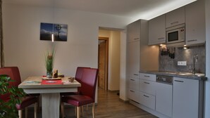 A modern kitchen with a microwave, sink, and cabinets. There is a dining table with chairs and a plant on it. - Ferienwohnung in Traumhafter Bergkulisse - Appartements Wacker (Bichlbach)