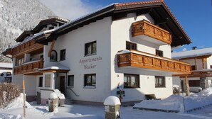 A multi-story building with balconies and a sign reading "Apartments Wacker". - Ferienwohnung in Traumhafter Bergkulisse - Appartements Wacker (Bichlbach)