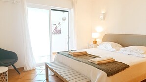 Ett hotellrum med en säng, en bänk, en stol och utsikt över Eiffeltornet genom fönstret.