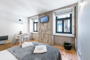 Un dormitori modern amb un llit, un escriptori i una televisió.