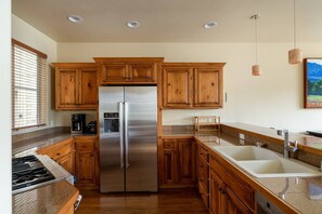 A modern kitchen with wooden cabinets, stainless steel appliances, granite countertops, and a large sink. - Great Ketchum Condo next to bike path & greenbelt (Ketchum)