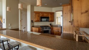 A kitchen with granite countertops, wooden cabinets, a stainless steel stove, and pendant lights. - Great Ketchum Condo next to bike path & greenbelt (Ketchum)
