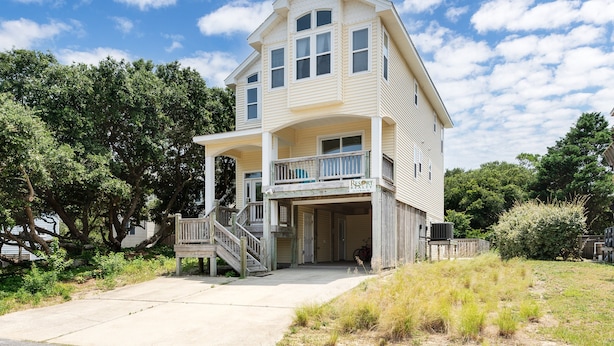 A two-story building with a covered porch and a staircase leading to the entrance. - 1767 - Fox Snooze - Corolla Retreat | Pool, Hot Tub & Beach Walk (Corolla)