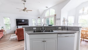 A modern kitchen with white cabinetry, a granite countertop, and a built-in dishwasher. - 1767 - Fox Snooze - Corolla Retreat | Pool, Hot Tub & Beach Walk (Corolla)