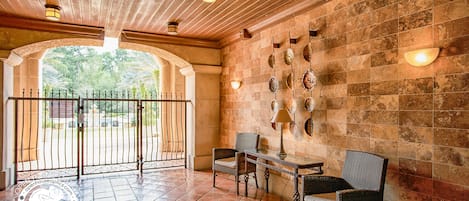 An indoor patio area with a tiled floor, a wrought iron gate, and a wall decorated with seashells.