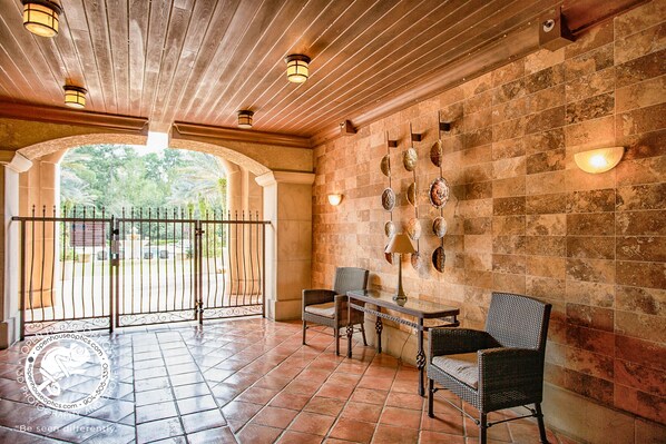 Un patio interior con suelo de baldosas, una reja de hierro forjado y una pared decorada con conchas marinas.