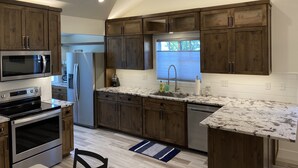 A modern kitchen with wooden cabinets, stainless steel appliances, and a granite countertop. - ***NEW*** Charming home located in Downtown Bend! (Bend)