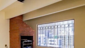 A room with a brick fireplace, a barred window, and a tiled floor. - In the best place in higienopolis 1 bedroom 1vaca (SP)
