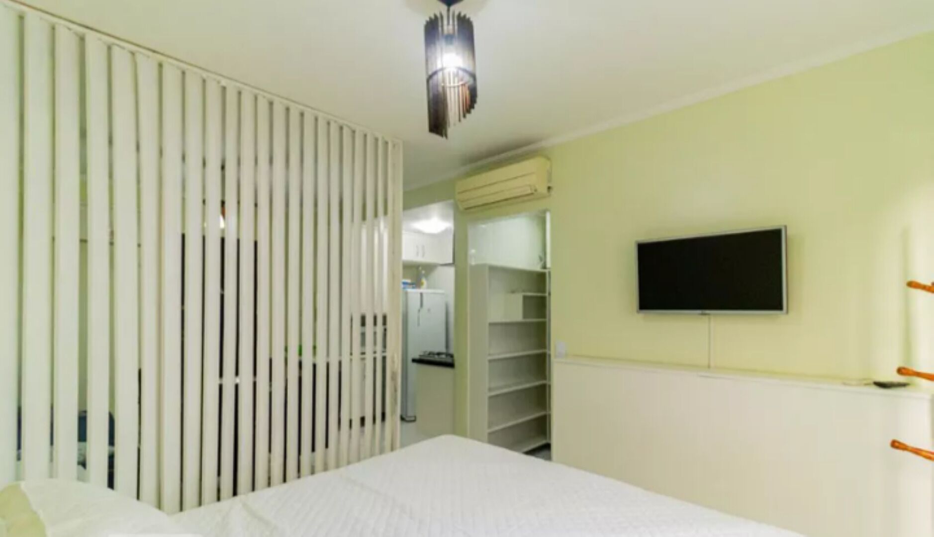 Une chambre à coucher comprenant un lit, une armoire, un téléviseur et un ventilateur de plafond.