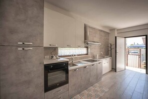 A modern kitchen with built-in appliances, a large window, and a view of the outside.