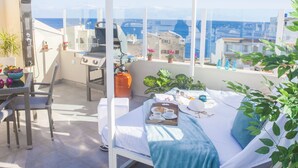 Ein Balkon mit Bett, Grill und Meerblick.