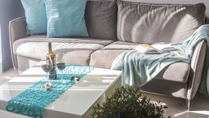 Ein modernes Wohnzimmer mit grauem Sofa, Türkis-Kissen, einem weißen Couchtisch und einem Buch.