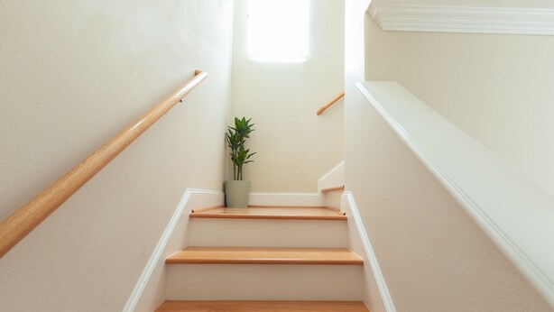 Een trap met houten treden en witte wanden.