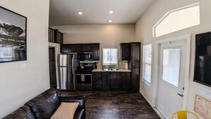 A compact kitchen with dark cabinets, stainless steel appliances, and a small dining area.