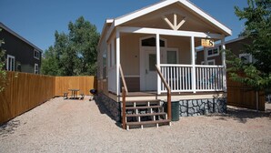 A small, single-story cabin with a porch and a stone foundation.